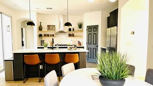 A modern kitchen with a central island, bar stools, and pendant lighting. - Huge Home near Old Folsom, Pet & Family Friendly (Folsom)