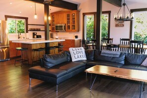Eine moderne Küche mit Holzschränken, einer Bar und einem Essbereich mit einer schwarzen Ledersofa und einem Tisch.