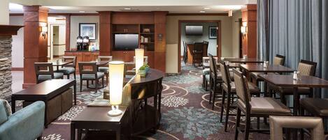 A hotel lobby with a seating area, a television, and a coffee station.