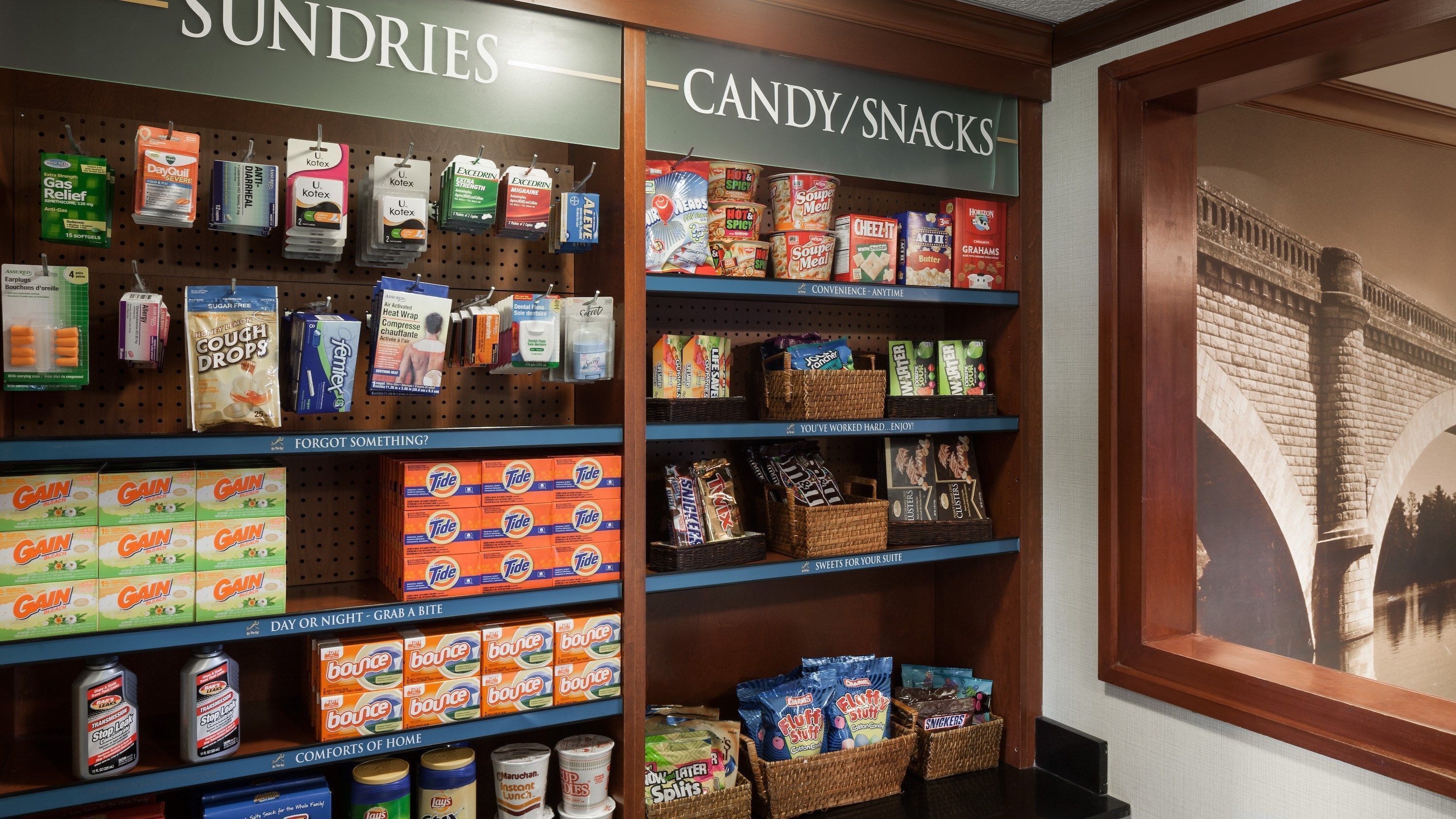 A store display with shelves of sundries and candy/snacks, including brands like Tide and Snickers.
