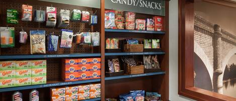 A store display with shelves of sundries and candy/snacks, including brands like Tide and Snickers.