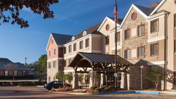 A multi-story hotel with a stone facade, a covered entrance, and a parking lot.