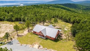 A rustic cabin with a metal roof, surrounded by dense forest and a view of distant mountains. - Log Cabin with Million Dollar View! “The Time Out” Secluded property (tuskahoma)
