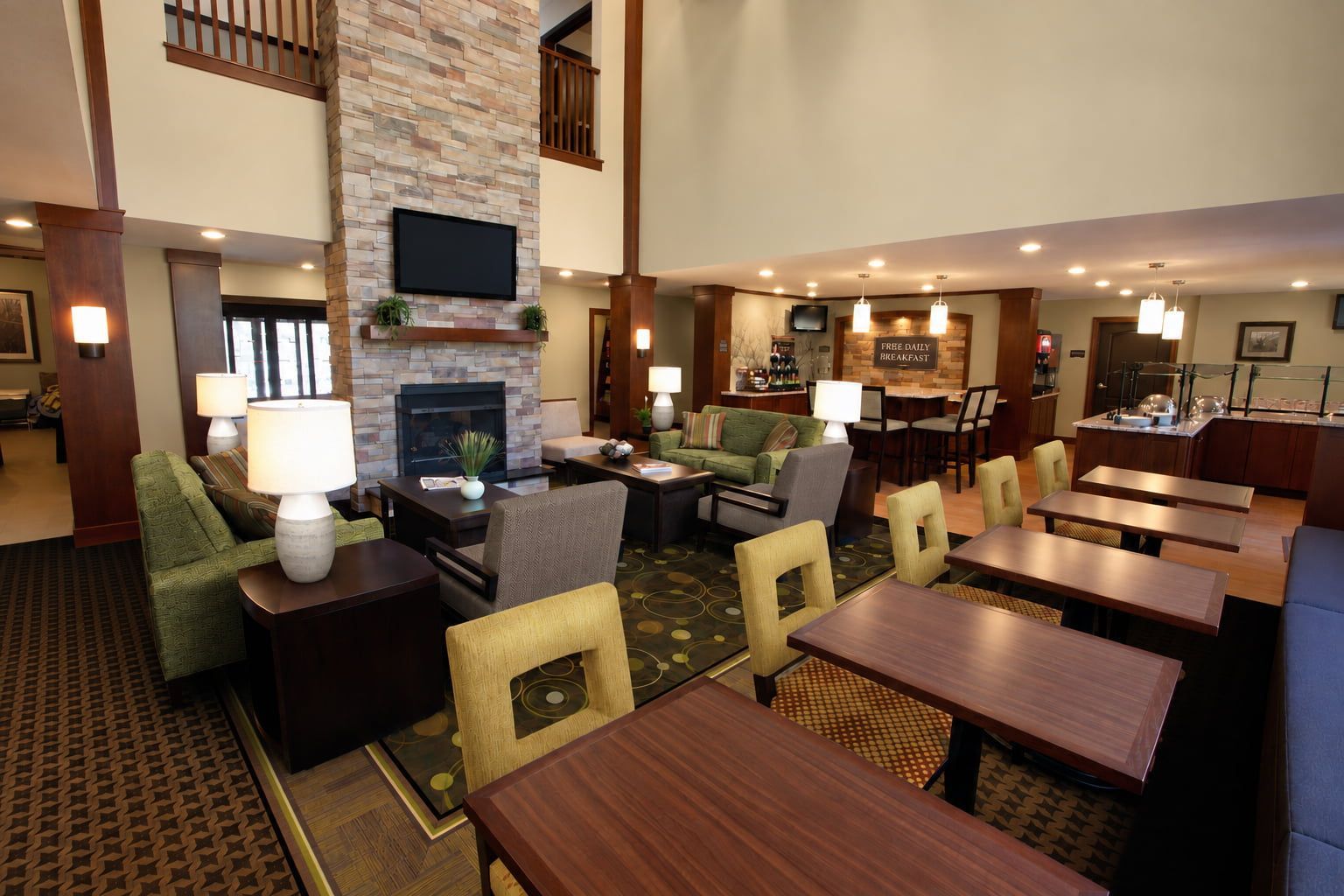 A hotel lobby with a fireplace, seating area, and a bar.