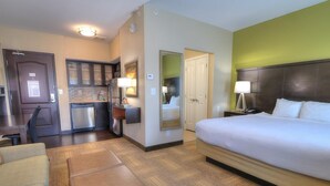 Une chambre d’hôtel comprenant un lit, un canapé, une petite table, une kitchenette et une salle de bain.