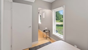 A bedroom with a large window, a bedside table, and a door leading to another room. - Beautiful Modern home peaceful location (Alberta Beach)