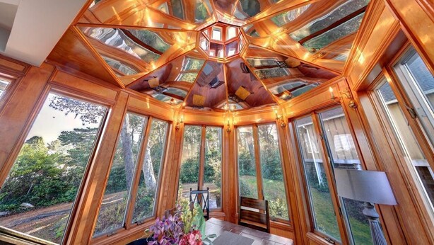 Una habitación con estructura de techo de madera, ventanas amplias y vistas al exterior.
