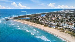 An aerial view of a coastal town with a beach, houses, and a marina. - 3 Bedroom Central Beachside Kingscliff Apartment with Pool (Kingscliff)