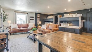 A modern living room with a wooden coffee table, two brown leather sofas, a dark wooden bench, and a large window. - Spacious Group Retreat | 3 Kings | Sleeps 25 (Ft. Worth)
