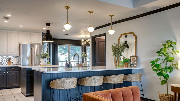 A modern kitchen with a central island, bar stools, and a seating area with a sofa. - Spacious Group Retreat | 3 Kings | Sleeps 25 (Ft. Worth)