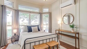 A bedroom with a bed, bedside tables, a mirror, and a window with curtains. - Spacious Group Retreat | 3 Kings | Sleeps 25 (Ft. Worth)