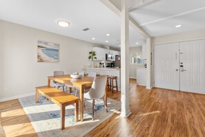 A modern kitchen with white cabinets and a dining area with a wooden table and benches.