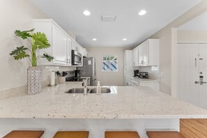 A modern kitchen with white cabinetry, a granite countertop, and a central island with seating.