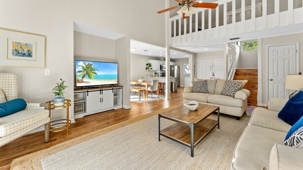 A spacious living area with a television, sofa, coffee table, and a ceiling fan.