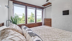 Un dormitorio con una cama grande, un aparador de madera y una ventana con vistas a la vegetación.