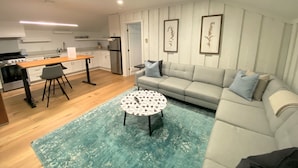 Un salon moderne avec un canapé, une table basse et un coin cuisine à l’arrière-plan.
