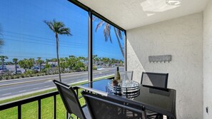 Un balcon avec une table, des chaises et une vue sur une route et des palmiers.