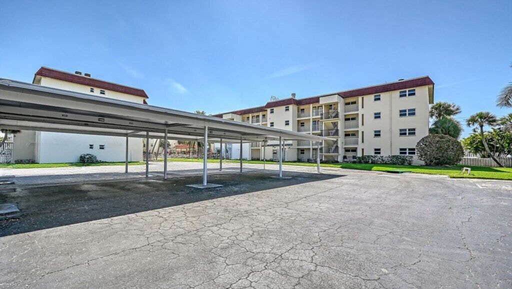 Un espace de stationnement doté d’une allée couverte menant à un bâtiment à plusieurs étages et agrémenté de balcons.
