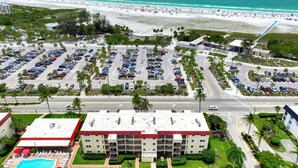 Ett hotell med en swimmingpool, flera parkeringsplatser och utsikt över stranden.