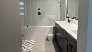 Un baño moderno con ducha, bañera y tocador con espejo.