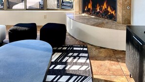 Un salon moderne doté d’une grande fenêtre, d’une cheminée et offrant une vue sur les montagnes.