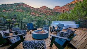 Une terrasse dotée de mobilier d’extérieur, d’un foyer et offrant une vue sur des collines rouges.