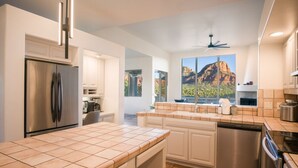 Une cuisine moderne dotée d’un grand îlot central, d’appareils électroménagers intégrés et offrant une vue sur une montagne.