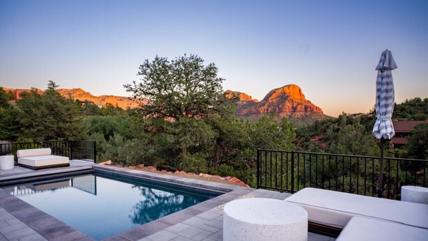 Une piscine agrémentée d’un foyer, un espace salon extérieur et une vue sur les montagnes.
