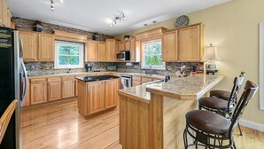 Una cocina moderna con armarios de madera, encimera de granito y una isla integrada con taburetes de bar.