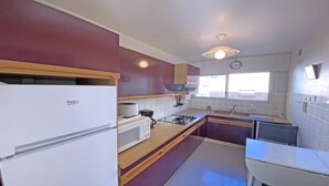 Eine kleine Küche mit Kühlschrank, Herd, Mikrowelle und Spüle.