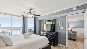 A bedroom with a bed, a dresser, a mirror, and a view of the beach. - Oceanfront condo with full balcony - 2 blocks to shops & restaurants - COV 120! (Folly Beach)