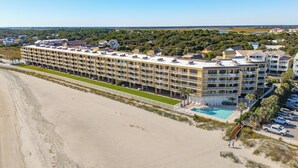 A beachfront hotel with multiple balconies, a swimming pool, and a beach access walkway. - Oceanfront condo with full balcony - 2 blocks to shops & restaurants - COV 120! (Folly Beach)