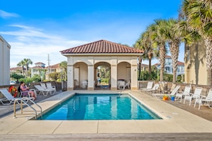 A pool area with lounge chairs and a covered seating area.