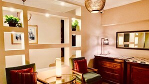 A dining area with a glass table, chairs, a wooden cabinet, and a mirror on the wall. - Kemet Boutique Hotel (Giza)