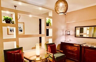 A dining area with a glass table, chairs, a wooden cabinet, and a mirror on the wall.