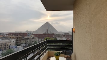A balcony with a view of a pyramid and surrounding buildings.