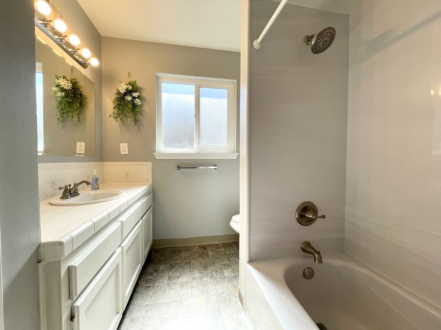 Un baño con bañera, ducha, lavamanos y ventana.