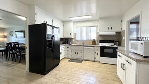 Una cocina moderna con alacenas blancas, un refrigerador negro, un microondas y una estufa.