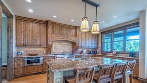 Una cocina amplia con armarios de madera, una isla grande con taburetes de bar y un ventanal que proporciona luz natural.