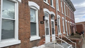 A row of brick townhouses with white trim, numbered doors, and a small set of stairs leading to the entrance. - Fireplace and Farmers Market Cozy! (Dubuque)
