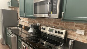 A modern kitchen with a stainless steel stove, a built-in microwave, and a coffee maker. - Fireplace and Farmers Market Cozy! (Dubuque)