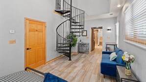 A modern interior with a spiral staircase, a blue sofa, and a wooden door. - 𖤓GrandVictorian 5000sqft Sale Sleeps23 ArcadeGameFloor BBQ𖤓 (Milwaukee)