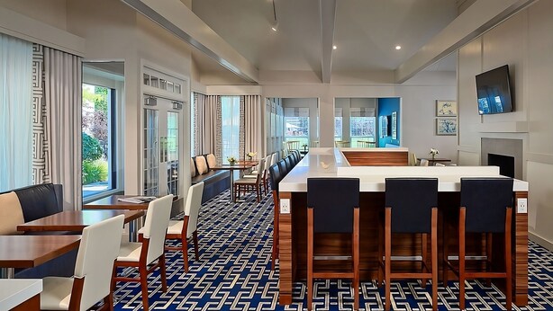 Un moderno vestíbulo de hotel con un mostrador de recepción alargado, varias zonas de estar y grandes ventanales con vistas al exterior.