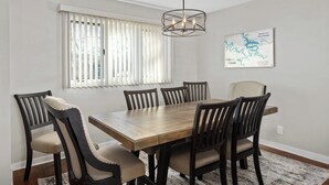 A dining area with a wooden table and chairs, a hanging light fixture, and a map on the wall.