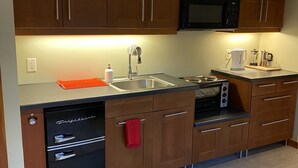 A compact kitchen with wooden cabinets, a built-in microwave, a dishwasher, and a coffee maker.