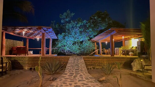 An outdoor area with a stone pathway leading to two covered structures, each with seating and tables. - Amazing private beachfront Village (Troncones)