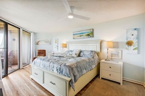 A bedroom with a bed, a nightstand, a chair, and a ceiling fan.