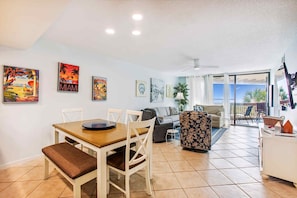 A spacious living area with a dining table, sofa, and balcony.