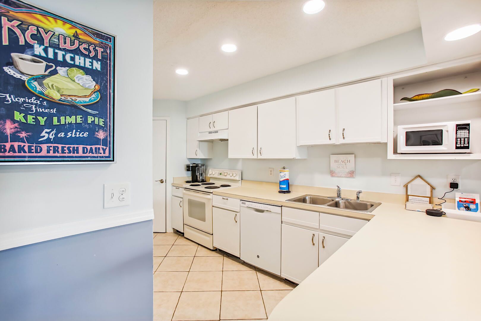 A modern kitchen with white cabinets, a stove, a microwave, and a sink.