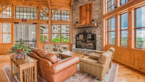 A spacious room with a fireplace, leather sofas, and large windows offering a view of the outside. - Soaring Eagle #403: 2 Bedrooms, 2 Full Baths (Snowshoe)